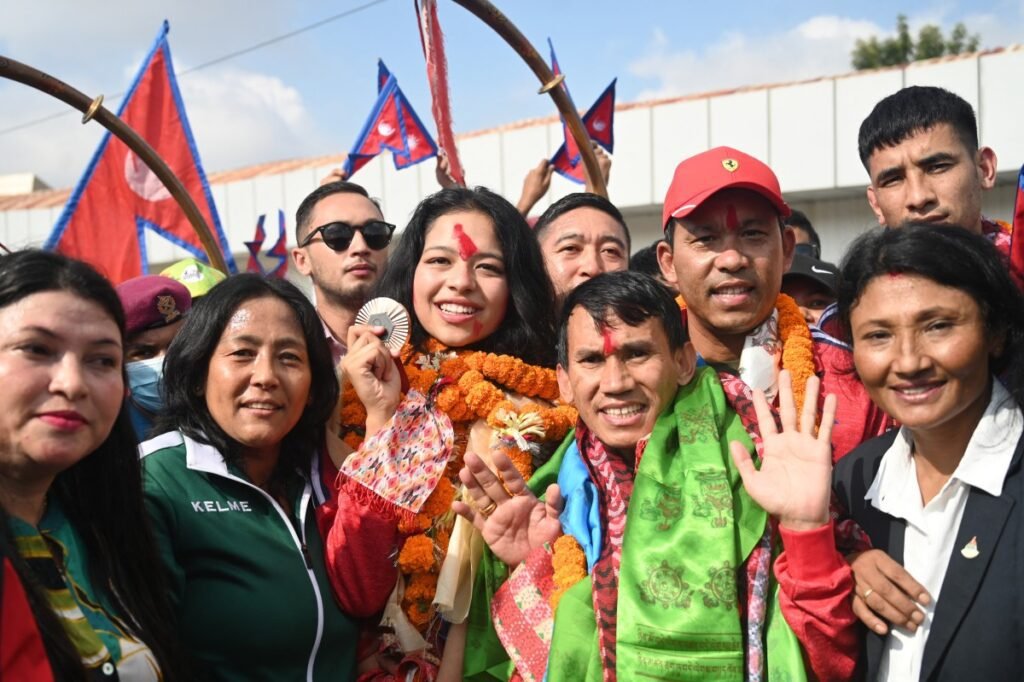 Palesha Goverdhan (C) poses with her medal upon her arrival at the Kathmandu airport. [Prakash Mathema/AFP]